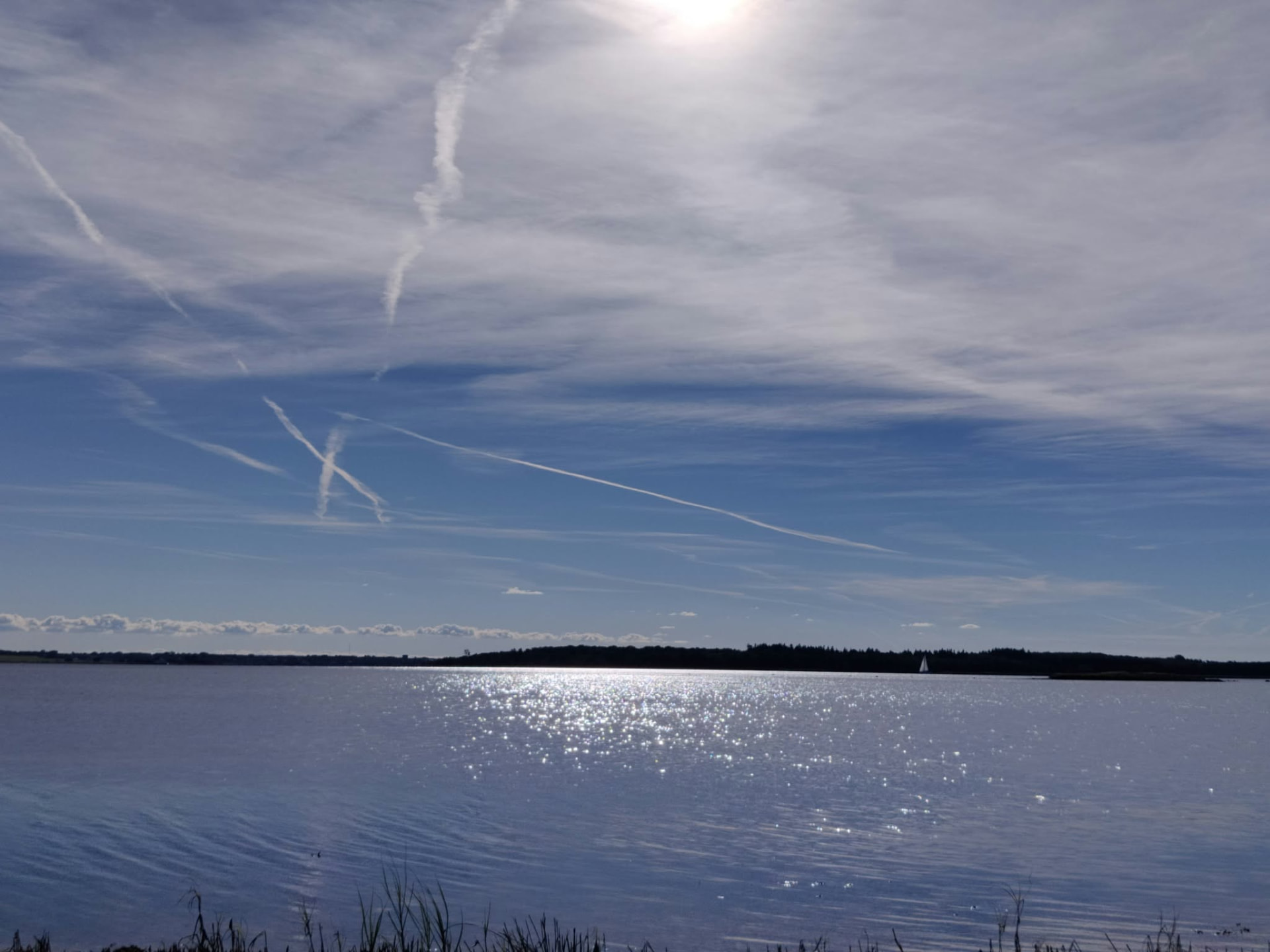 Solskin, der glimter på vandet ved Orø under en let skyet himmel